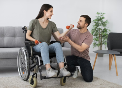 Man assisting a woman in a wheelchair with dumbbell exercises.